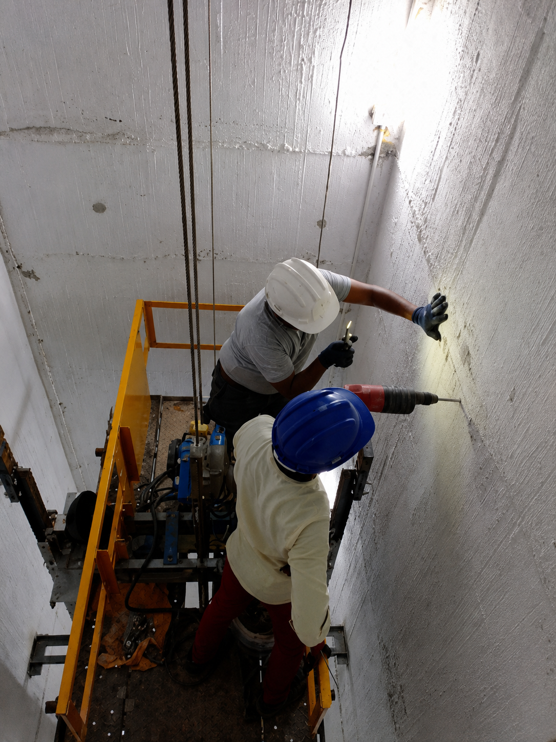 Two workers plastering the interior of an elevator shaft